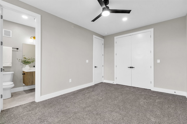 unfurnished bedroom featuring ensuite bath, ceiling fan, a closet, and carpet