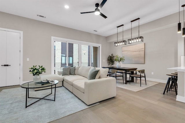 living room with ceiling fan and light hardwood / wood-style flooring