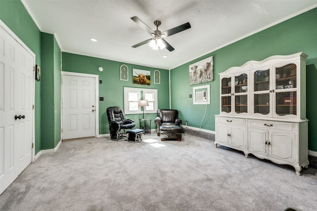 sitting room featuring a textured ceiling, ceiling fan, crown molding, and light carpet