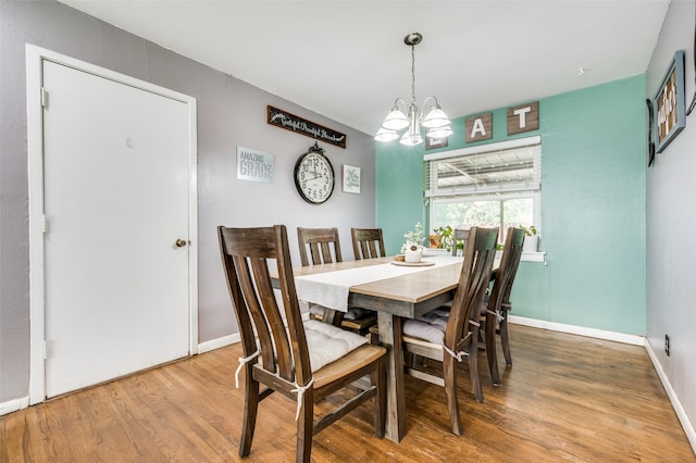 dining area with hardwood / wood-style floors and a chandelier