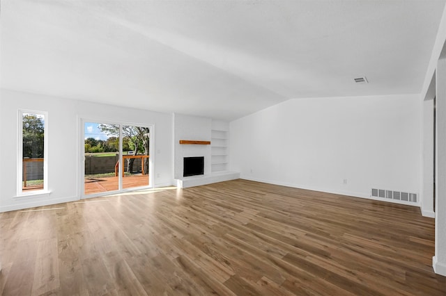 unfurnished living room featuring a fireplace, dark hardwood / wood-style flooring, vaulted ceiling, and built in features