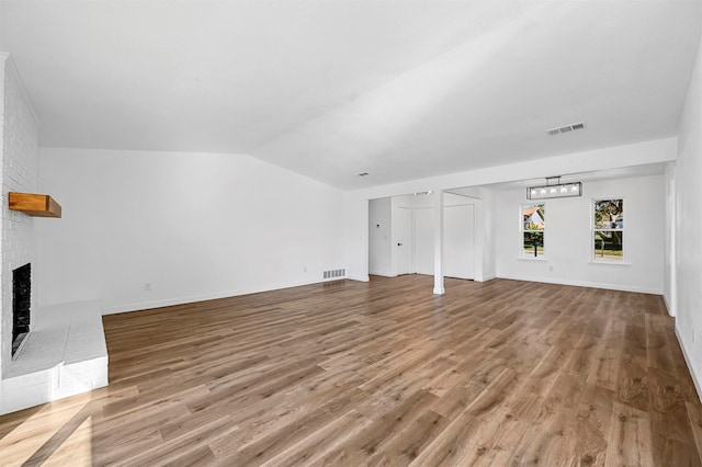 unfurnished living room featuring a fireplace, hardwood / wood-style floors, and vaulted ceiling