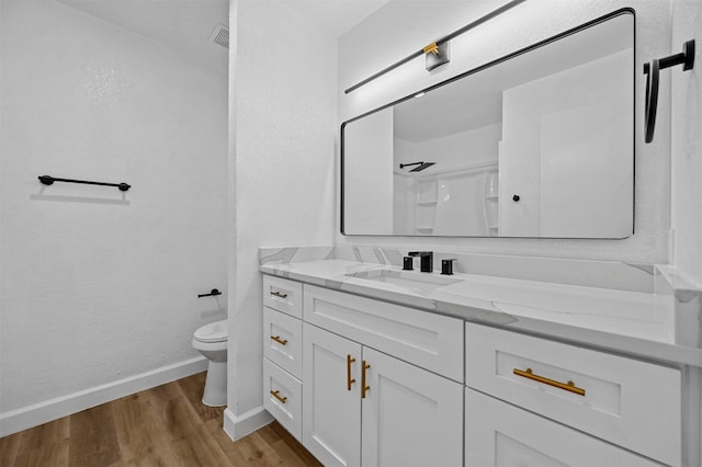 bathroom featuring hardwood / wood-style floors, vanity, toilet, and a shower