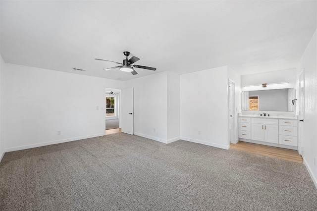 unfurnished bedroom featuring ceiling fan, light colored carpet, and ensuite bathroom