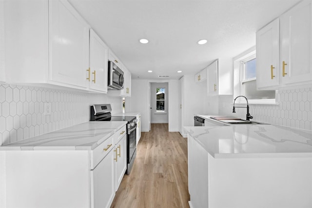 kitchen featuring stainless steel appliances, light stone counters, kitchen peninsula, light hardwood / wood-style floors, and white cabinets