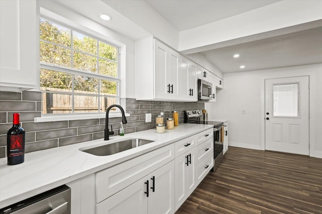 kitchen with decorative backsplash, light stone countertops, stainless steel appliances, sink, and white cabinetry