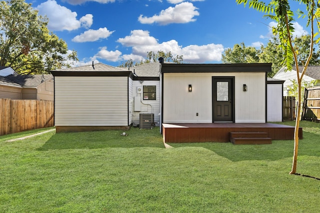 rear view of house featuring central AC unit and a yard