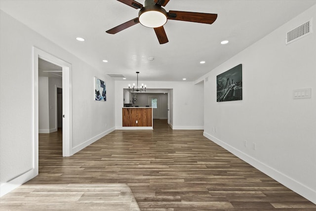 unfurnished living room with ceiling fan with notable chandelier and wood-type flooring