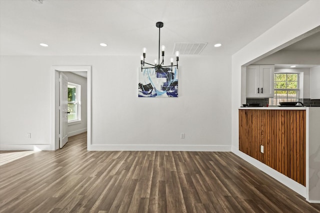 unfurnished dining area featuring dark hardwood / wood-style flooring and an inviting chandelier