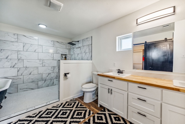 bathroom with hardwood / wood-style flooring, vanity, toilet, and a tile shower