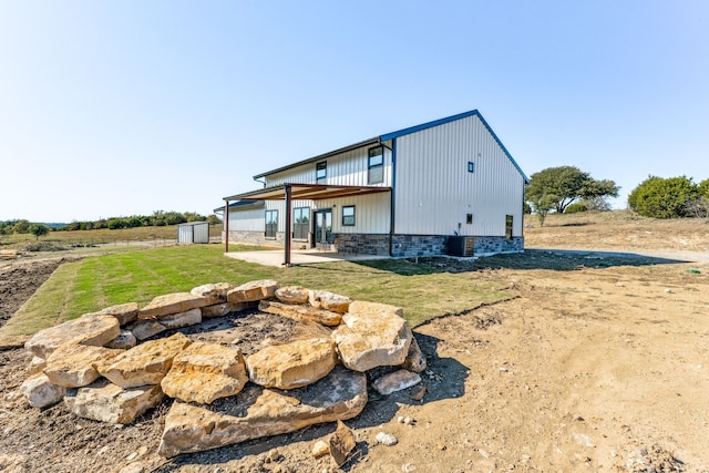 rear view of property with central AC unit and a yard