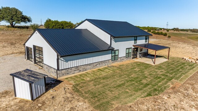 back of house with a yard, a storage unit, and a patio area