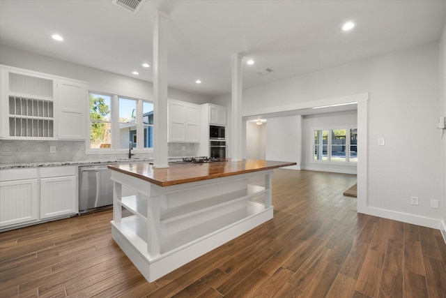 kitchen featuring white cabinetry, a center island, dishwasher, butcher block countertops, and decorative backsplash