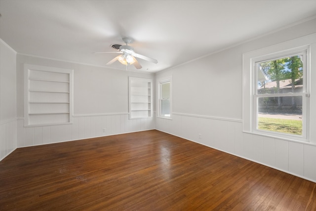 unfurnished room with built in shelves, ceiling fan, dark hardwood / wood-style flooring, and ornamental molding