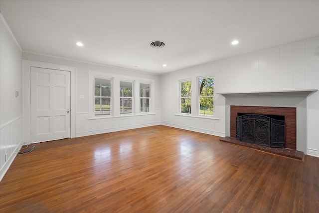 unfurnished living room with a brick fireplace, dark wood-type flooring, and ornamental molding