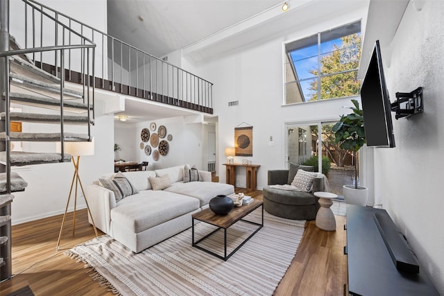 living room with a towering ceiling and wood-type flooring