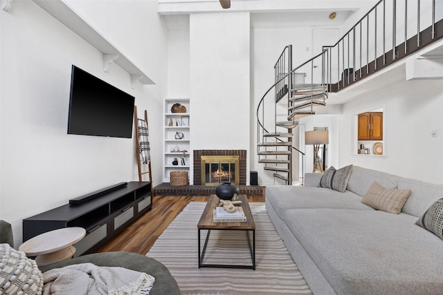 living room with wood-type flooring, a fireplace, and a towering ceiling