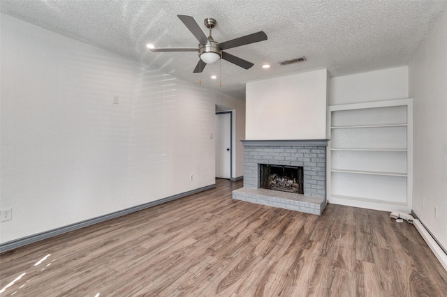 unfurnished living room featuring a fireplace, a textured ceiling, hardwood / wood-style flooring, and ceiling fan