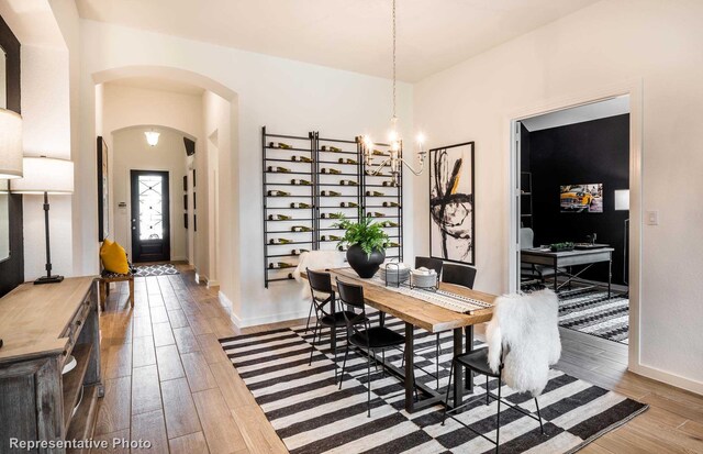 dining area with hardwood / wood-style floors and an inviting chandelier