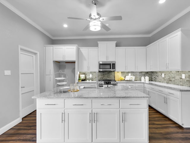 kitchen with stainless steel appliances, white cabinetry, and dark hardwood / wood-style floors