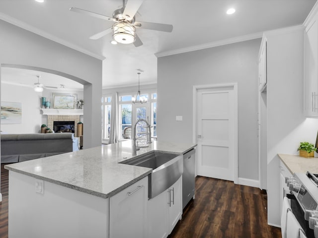 kitchen featuring white cabinetry, dishwasher, a brick fireplace, white range, and a center island with sink