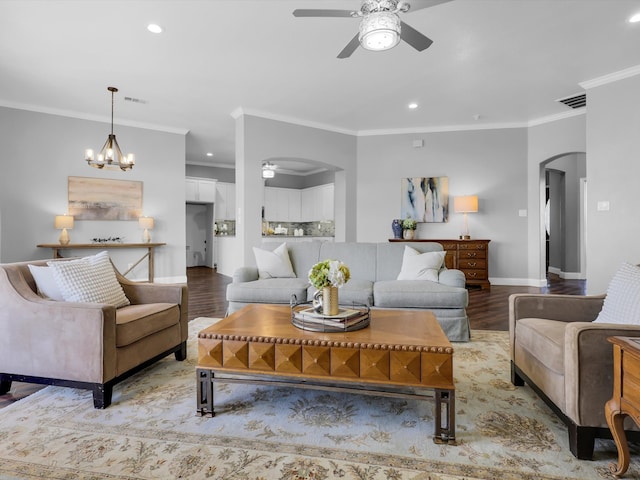 living room with crown molding, light hardwood / wood-style flooring, and ceiling fan with notable chandelier