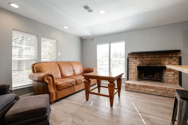 living room with light hardwood / wood-style floors and a brick fireplace