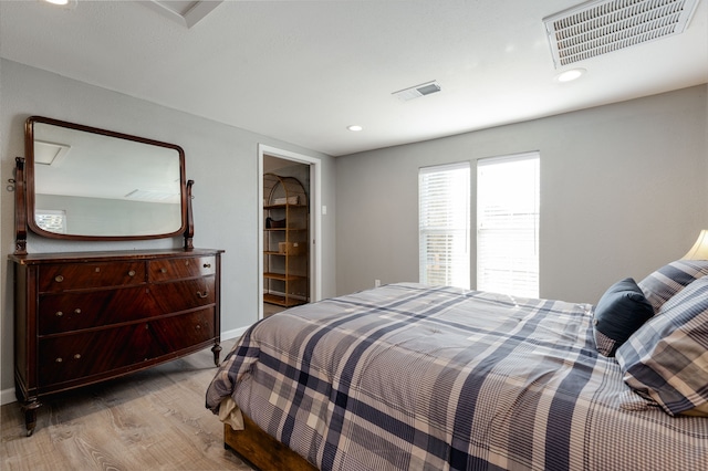 bedroom with light wood-type flooring, a walk in closet, and a closet