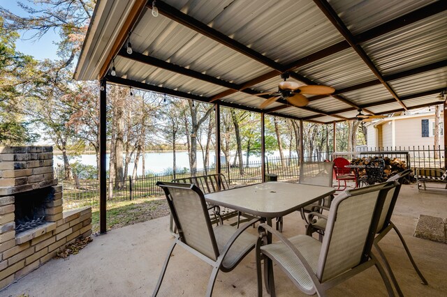 view of patio featuring a water view, exterior fireplace, and ceiling fan