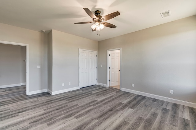 unfurnished bedroom with ceiling fan, a closet, and hardwood / wood-style flooring