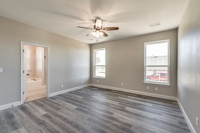 empty room with a wealth of natural light, dark hardwood / wood-style flooring, and ceiling fan