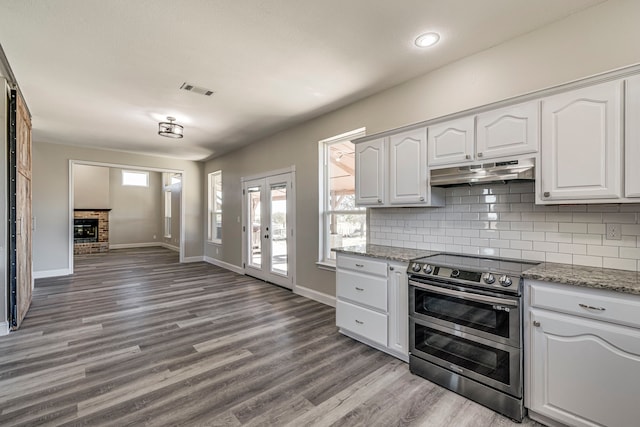 kitchen with light stone counters, light hardwood / wood-style flooring, white cabinets, and stainless steel electric range