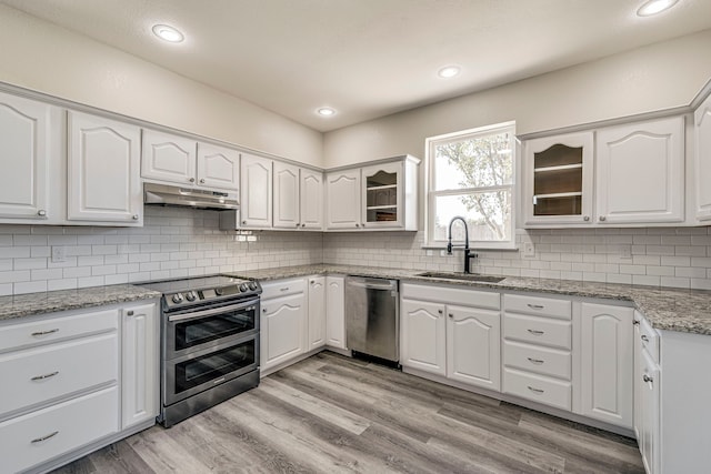 kitchen featuring backsplash, white cabinets, sink, light hardwood / wood-style floors, and stainless steel appliances