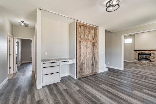 unfurnished living room with dark wood-type flooring and a brick fireplace