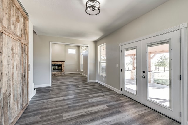 doorway to outside with a barn door, a fireplace, dark wood-type flooring, and french doors