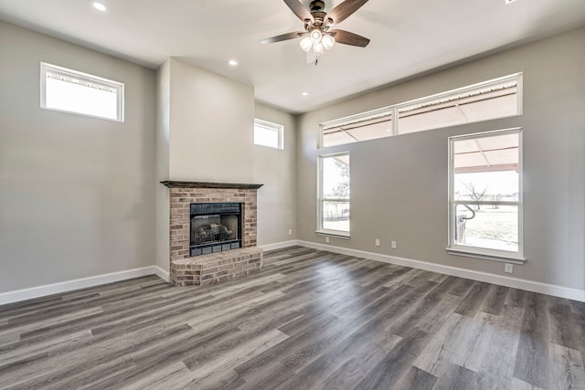 unfurnished living room featuring dark hardwood / wood-style flooring, a brick fireplace, and ceiling fan