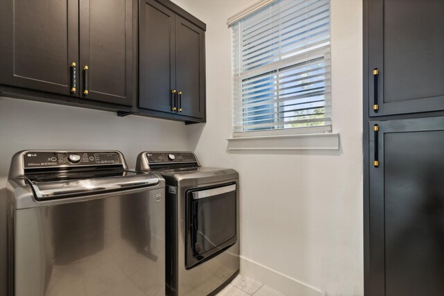 laundry area with washer and dryer, light tile patterned floors, and cabinets