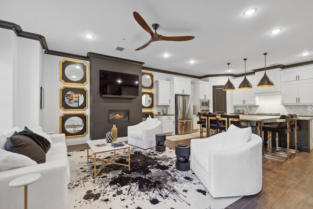 living room with a fireplace, ceiling fan, and crown molding