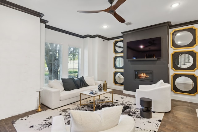 living room with dark hardwood / wood-style floors, a large fireplace, ornamental molding, and ceiling fan