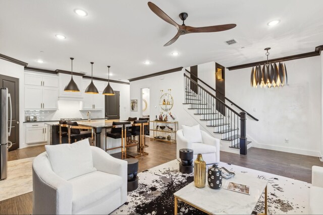 living room featuring ceiling fan, dark hardwood / wood-style flooring, and crown molding