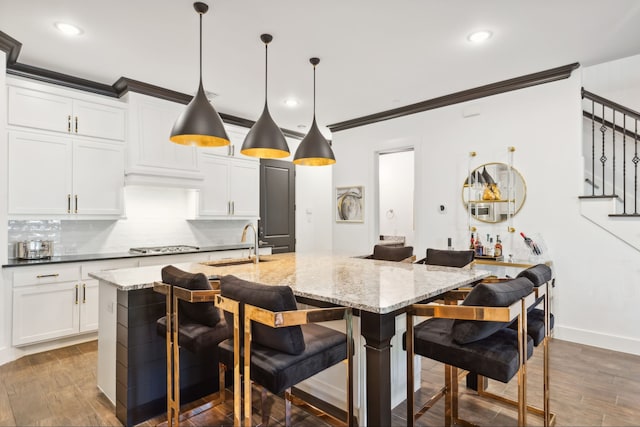 kitchen with pendant lighting, dark stone counters, a kitchen breakfast bar, dark hardwood / wood-style floors, and an island with sink