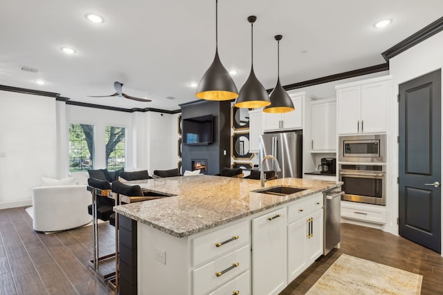 kitchen with appliances with stainless steel finishes, dark hardwood / wood-style floors, white cabinetry, and a kitchen island with sink