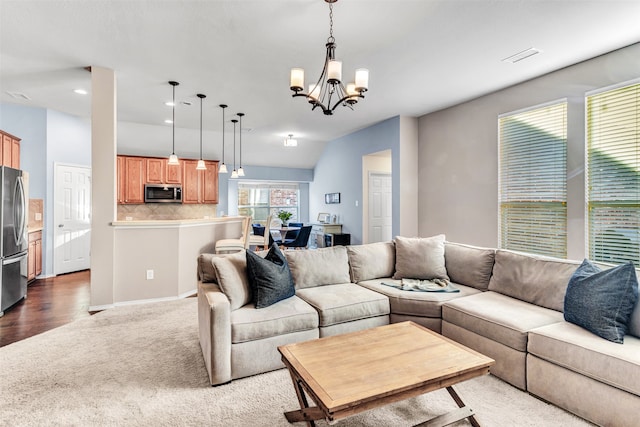 living room with hardwood / wood-style floors, lofted ceiling, and a notable chandelier