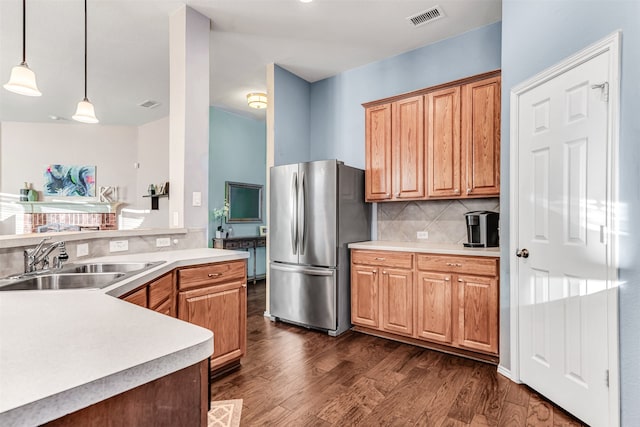 kitchen featuring stainless steel fridge, dark hardwood / wood-style flooring, sink, and hanging light fixtures