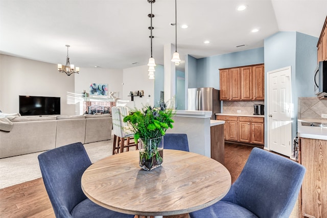 dining area with a brick fireplace, light hardwood / wood-style flooring, and an inviting chandelier