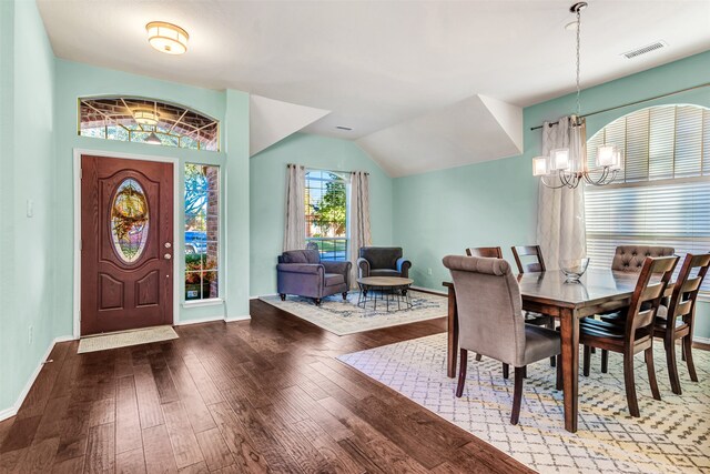 dining area featuring hardwood / wood-style floors, lofted ceiling, and a notable chandelier