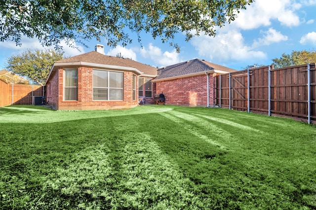 rear view of property featuring central air condition unit and a yard