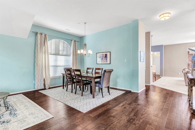 dining space with dark wood-type flooring and a notable chandelier