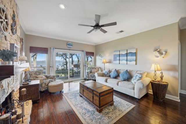 living room featuring ceiling fan, a fireplace, ornamental molding, and dark wood-type flooring