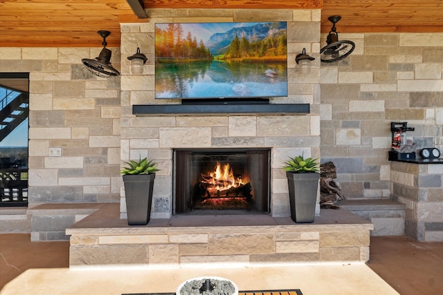 room details with an outdoor stone fireplace, concrete floors, and wood ceiling